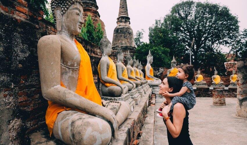 A woman with a child in front of buddha statues.