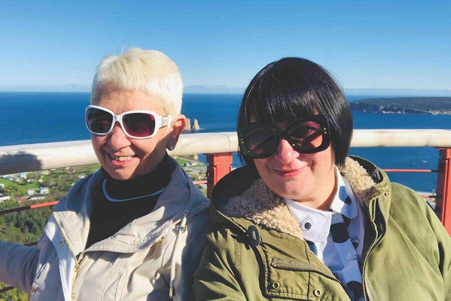 Two women posing for a selfie on a cliff overlooking the ocean.