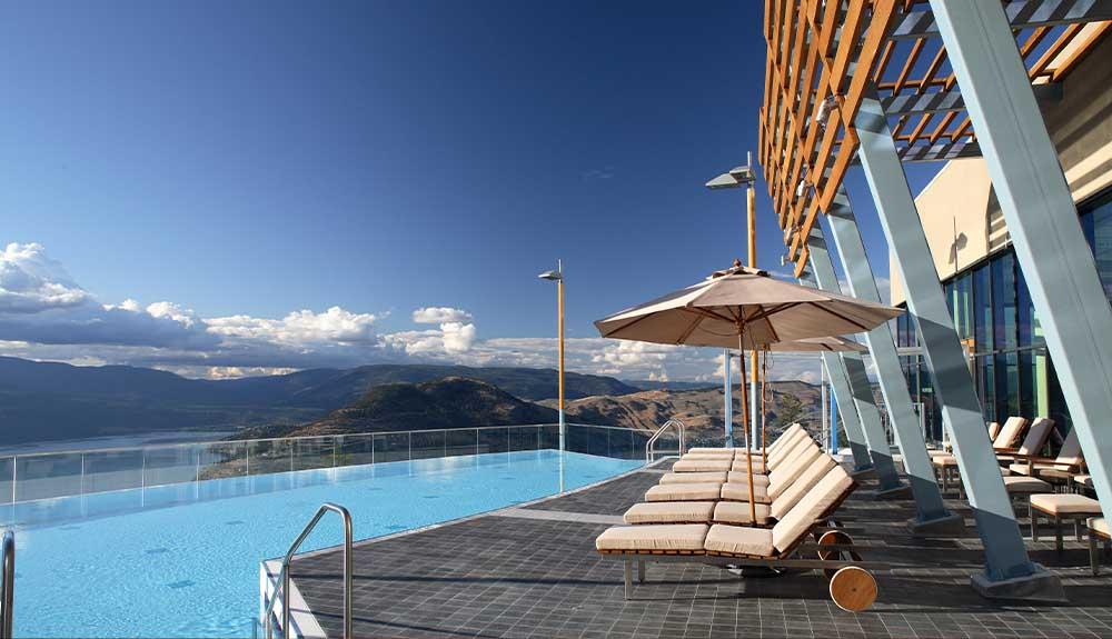 A pool with a deck chair and umbrella.