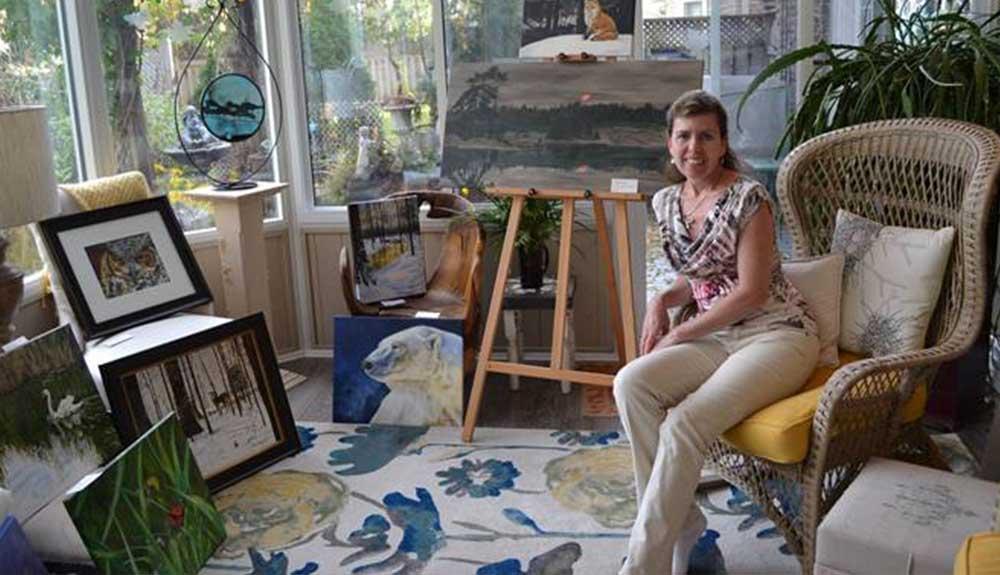 A woman sitting in a chair in a room full of art.