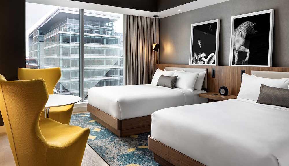 A hotel room with two beds and a yellow chair.