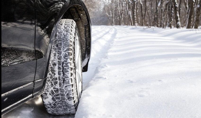 The tire of a car is covered in snow.