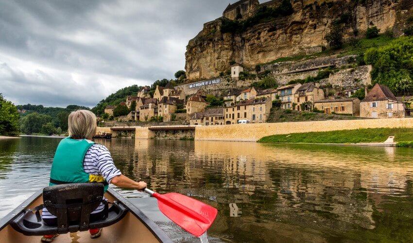 A woman is paddling a canoe down a river.