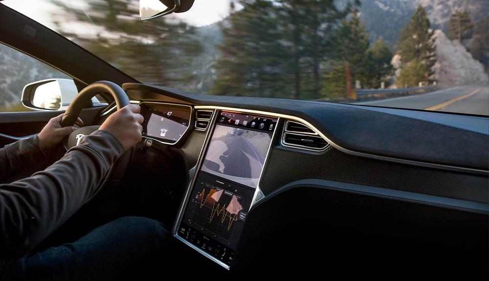 A man is driving a tesla model s.