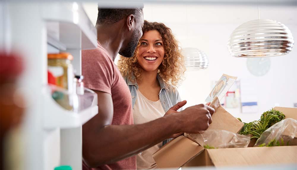A man and woman looking at a box of groceries.