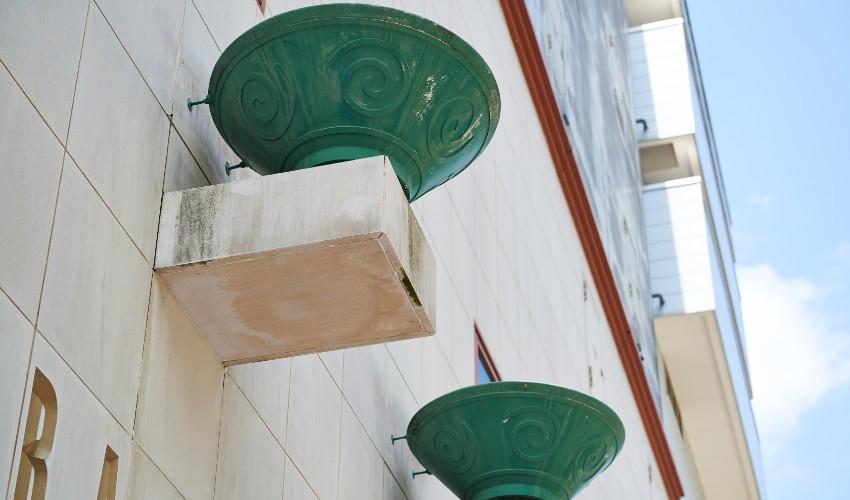 Awning-style balconies with decorative green patina on the underside, attached to a white building's facade.