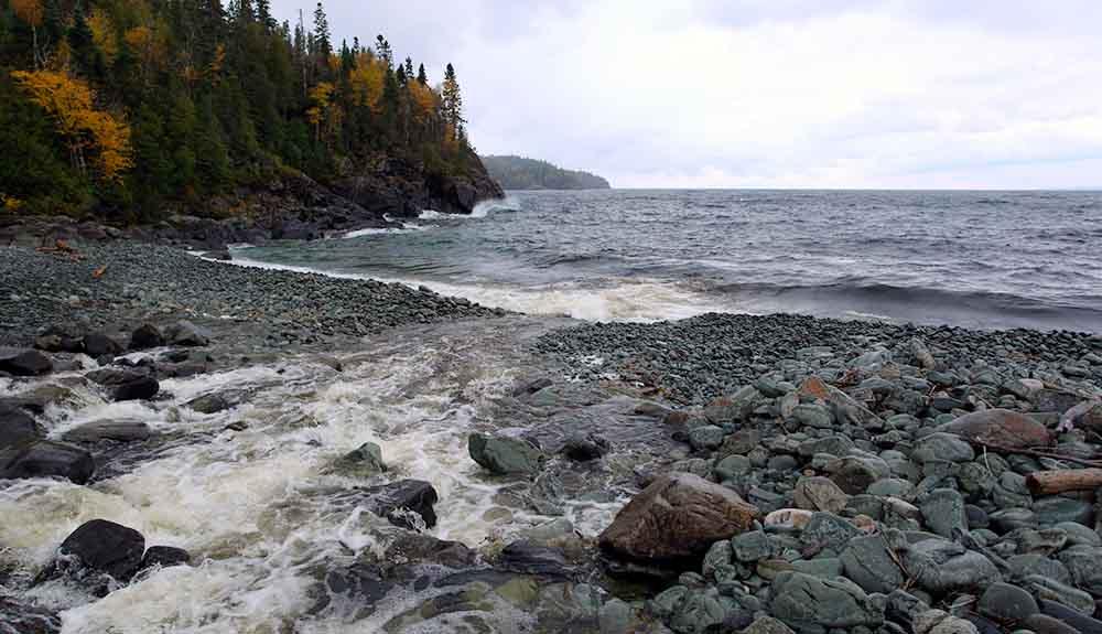 A rocky shore with a waterfall and rocks.