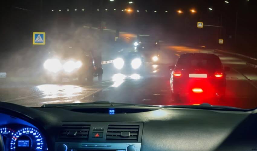 A car driving on a rainy road at night.