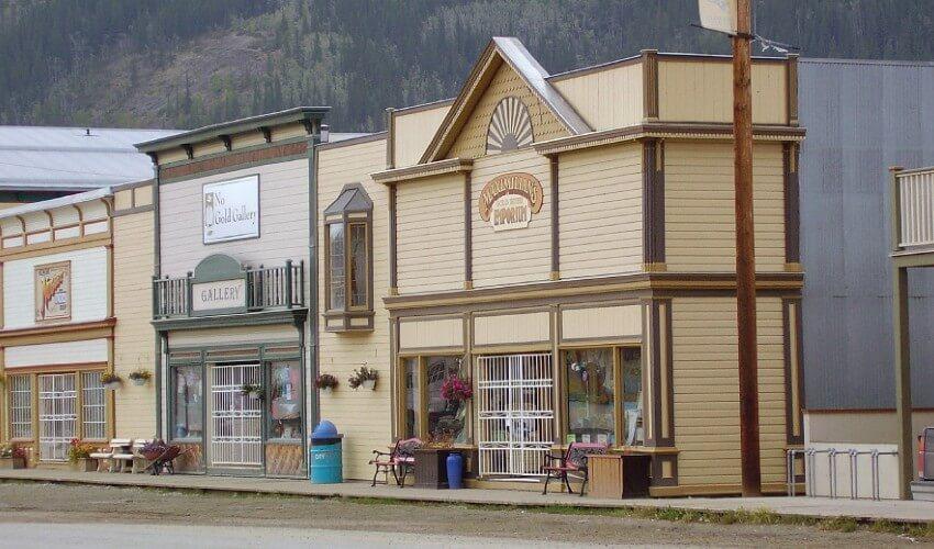 A row of buildings on a street with mountains in the background.