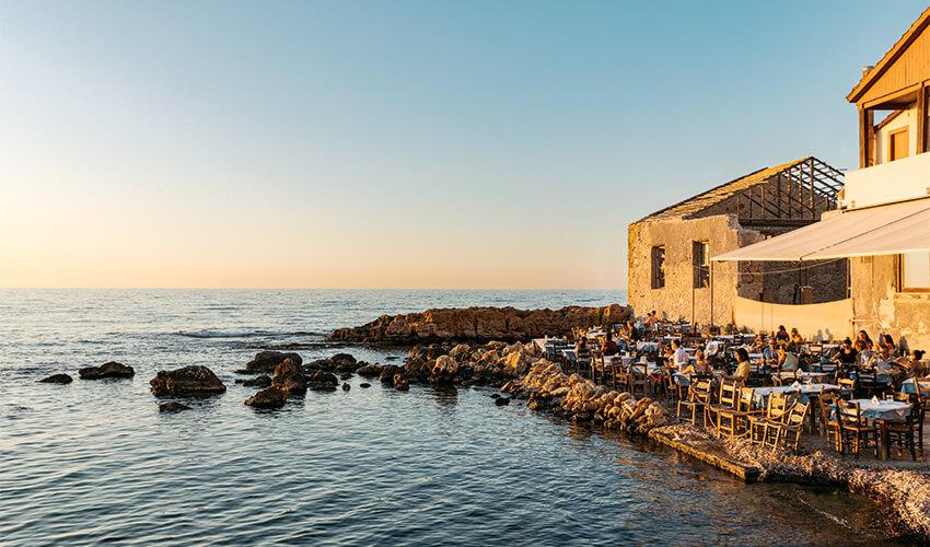 A restaurant with tables and chairs by the water.