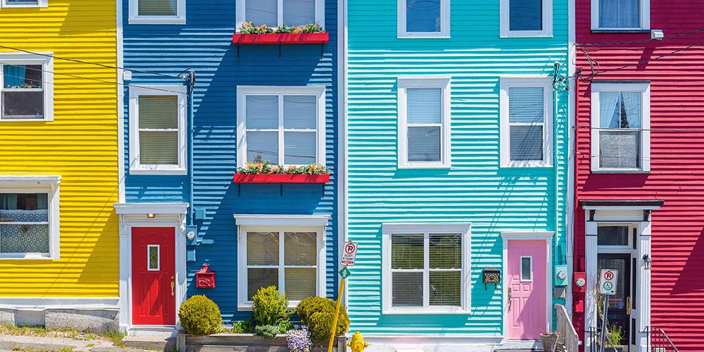 Row of colorful townhouses with vibrant facades under a clear sky.