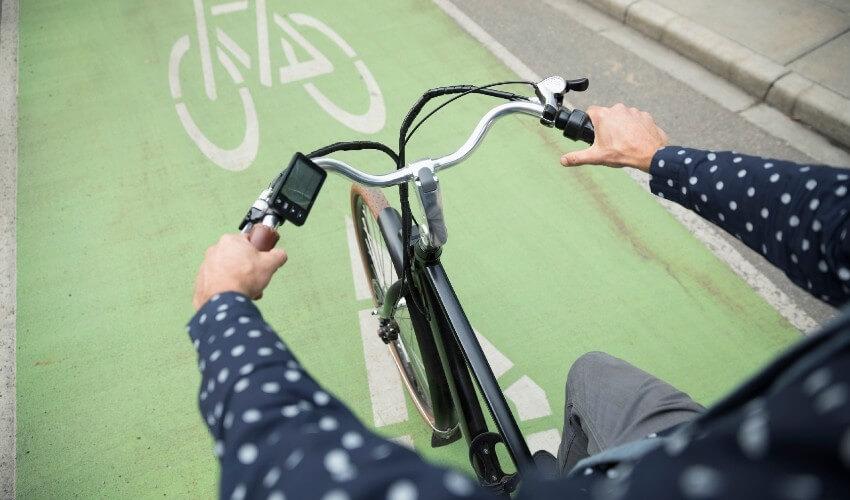 A man riding a bicycle on a green bike lane.