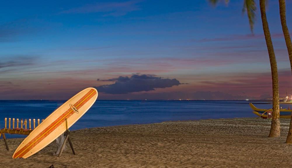 A surfboard on a beach at dusk.