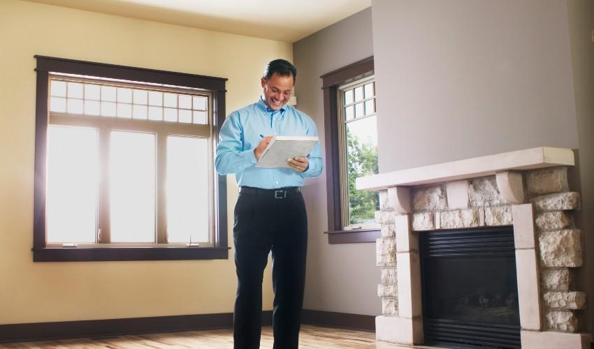 A man standing in front of a fireplace with a tablet.