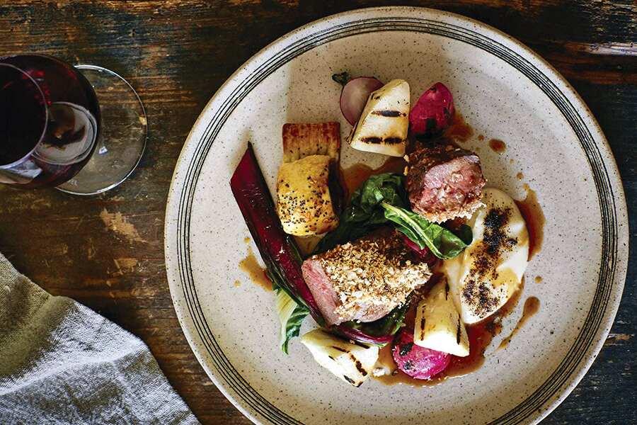 A plate with meat, vegetables and a glass of wine.