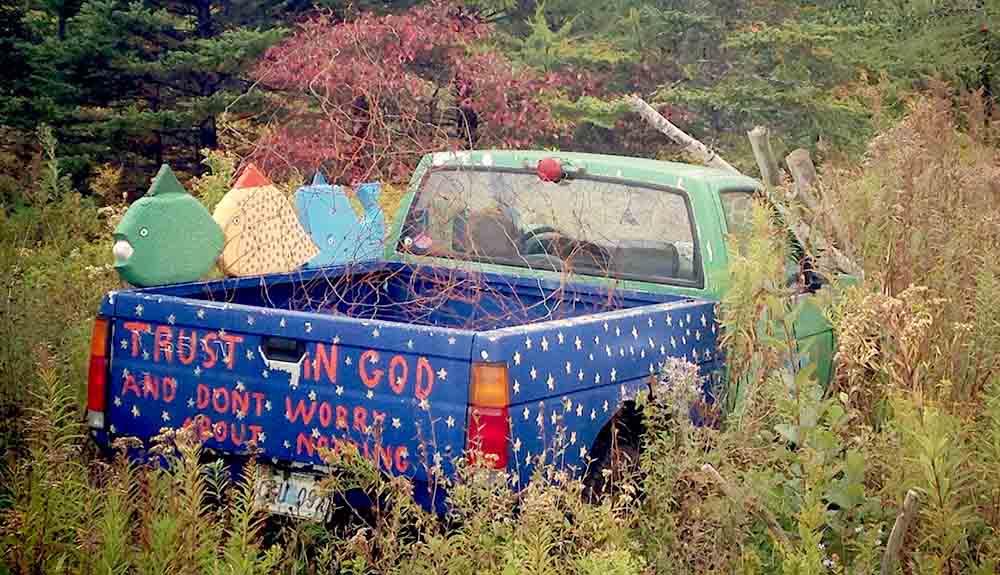 A blue truck is sitting in the middle of a field.