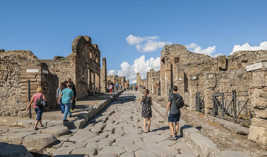 People walking down a cobblestone street in pompeii, italy.