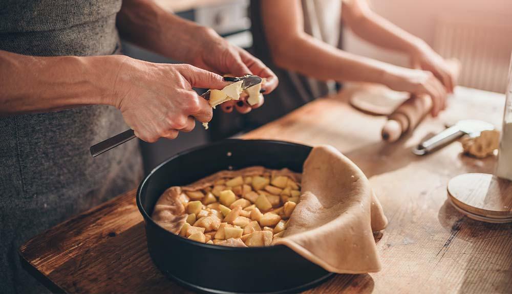 A woman is making a pie in a pan.