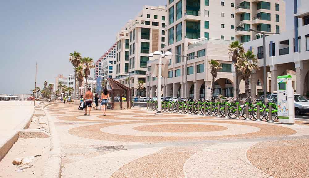 A sidewalk with bicycles and buildings in the background.