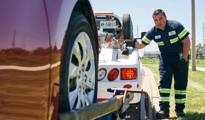 A tow truck operator securing a vehicle for transport.