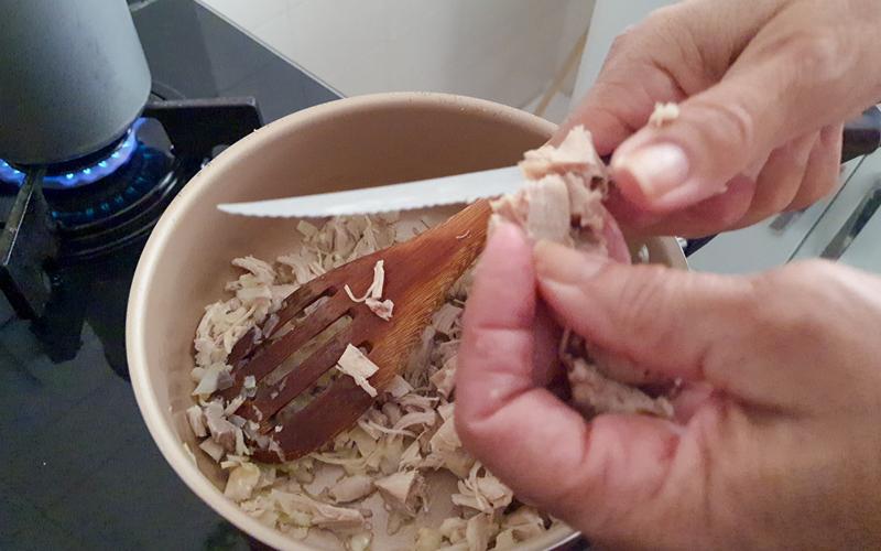 Top-down view of two hands preparing a meal with chicken.