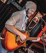 Musician playing an acoustic guitar onstage.