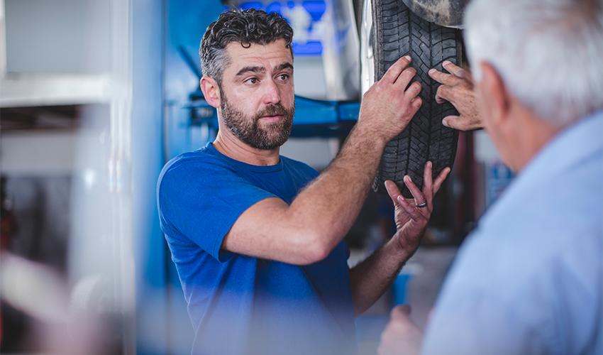 A mechanic inspecting a tire in a garage.