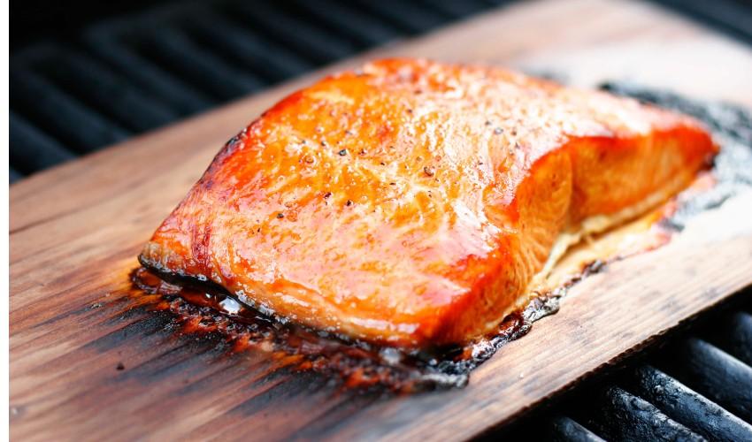 A piece of salmon is sitting on a wooden board.
