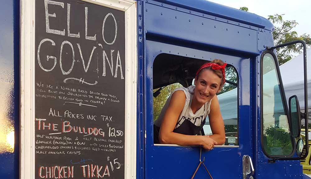 A woman standing in front of a food truck.