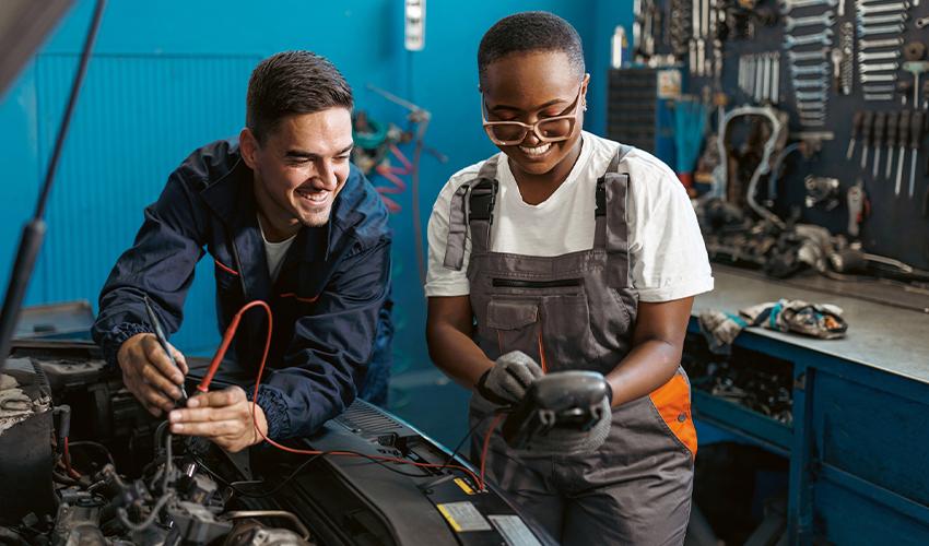 Two mechanics working on a car in a garage.