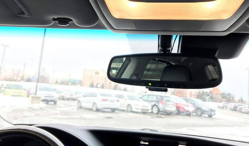 The rear view mirror of a car in a parking lot.