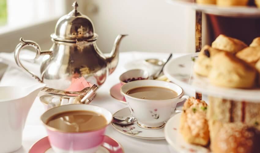 Tea and pastries on a table next to a silver teapot.