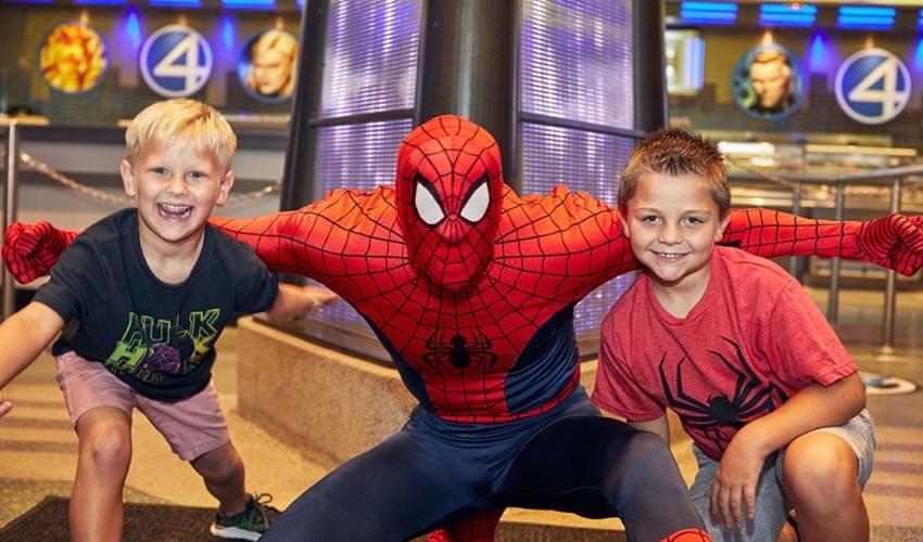 Two boys pose for a picture with a spider - man.