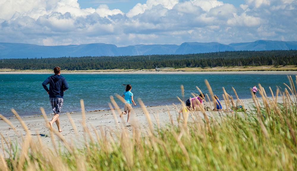 A group of people playing frisbee on a beach.