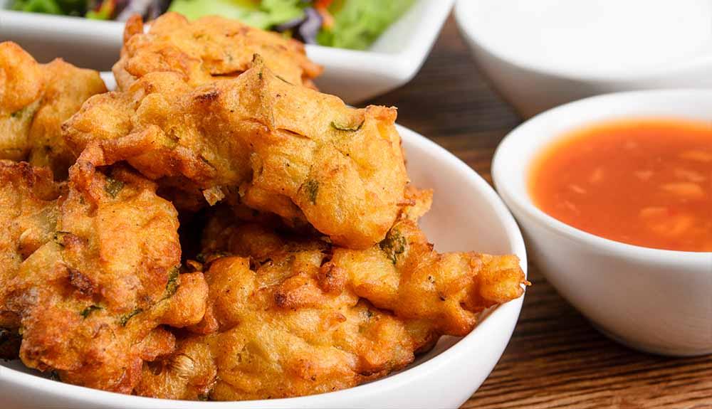 A bowl of fried calamari with sauce and salad.