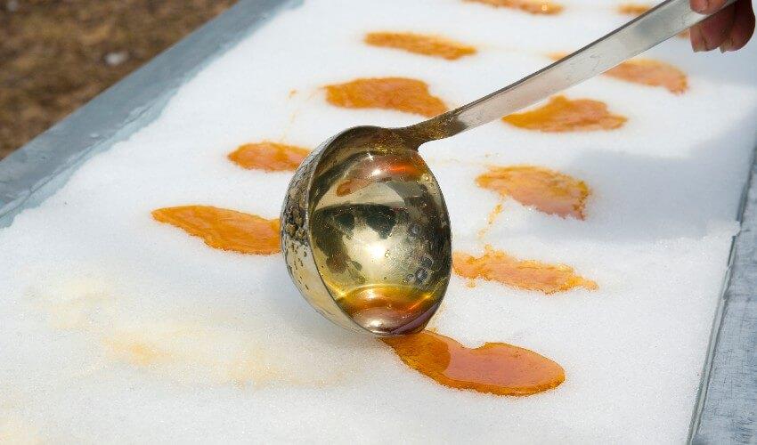 A person is pouring orange juice onto a tray of ice.