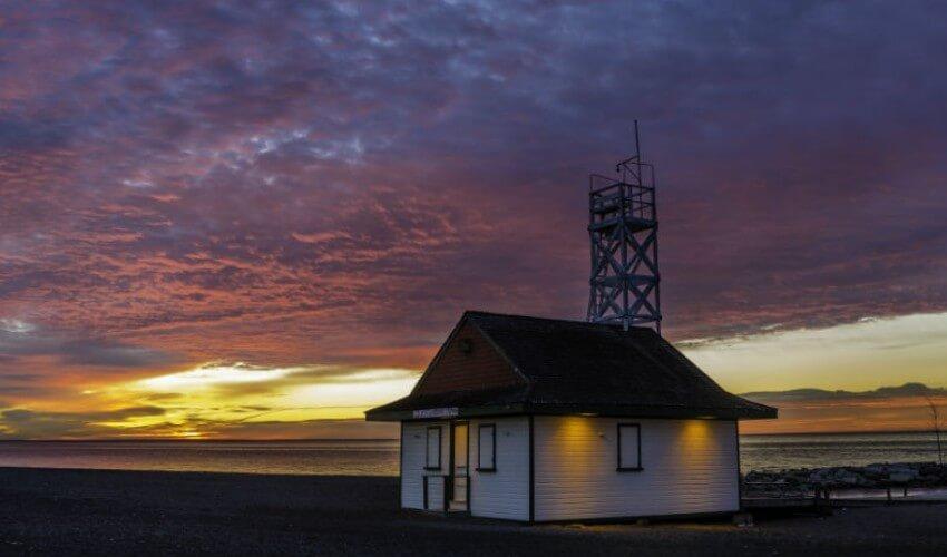 A small lighthouse on the beach at sunset.