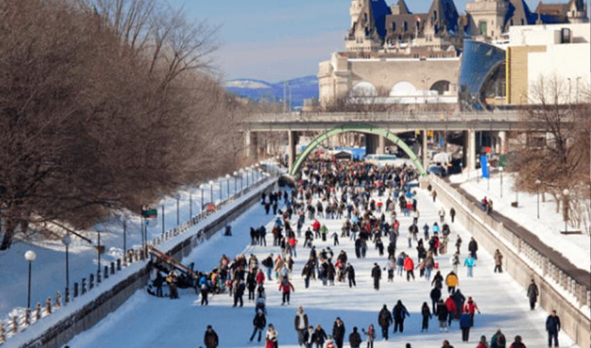 A group of people walking down a river in the snow.