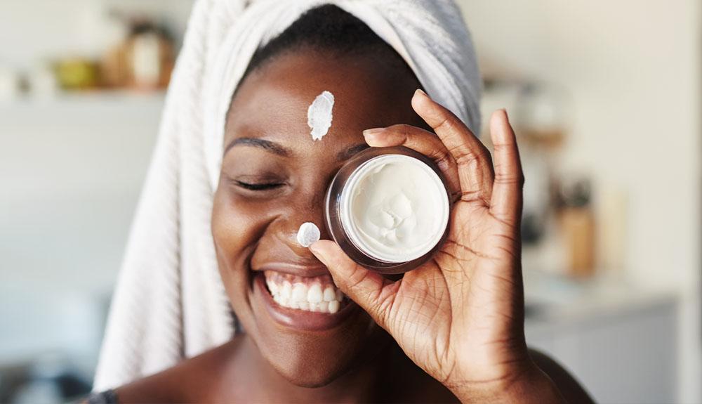 A woman is holding a jar of cream in her hand.