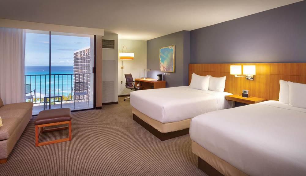A hotel room with two beds and a view of the ocean.