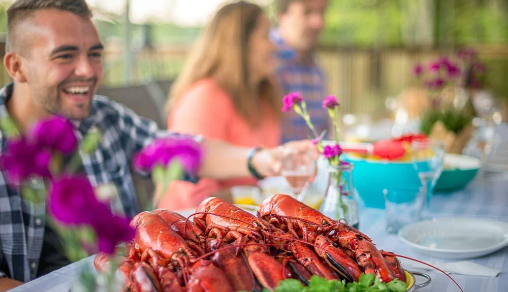 A group of people sitting at a table with lobsters.