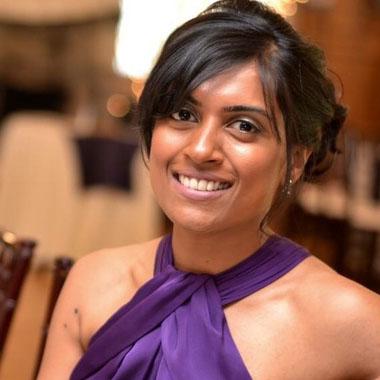 A woman in a purple dress smiling for the camera.