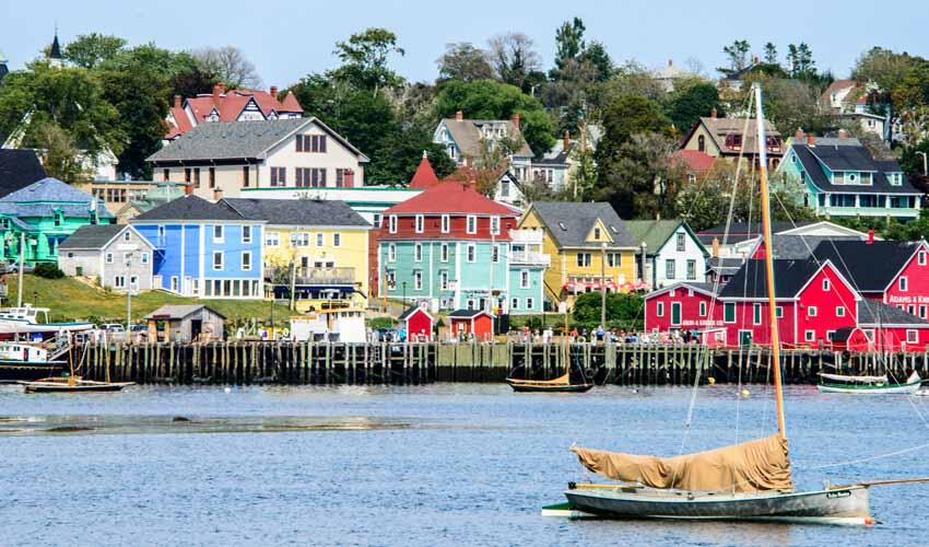 A boat sails past colorful houses on the water.
