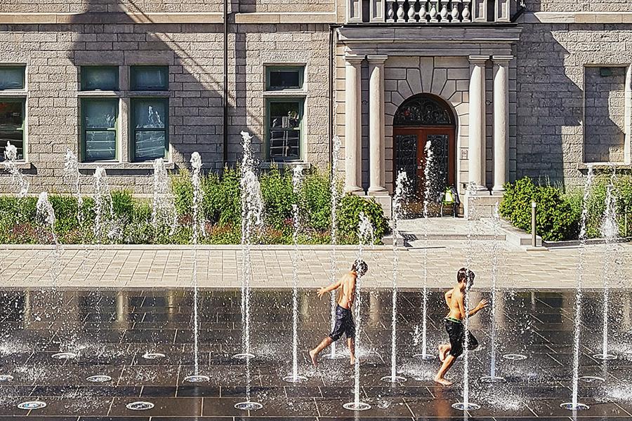 Two boys play in the fountain in front of a building.