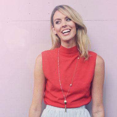 A blonde woman wearing a red top and a blue skirt.