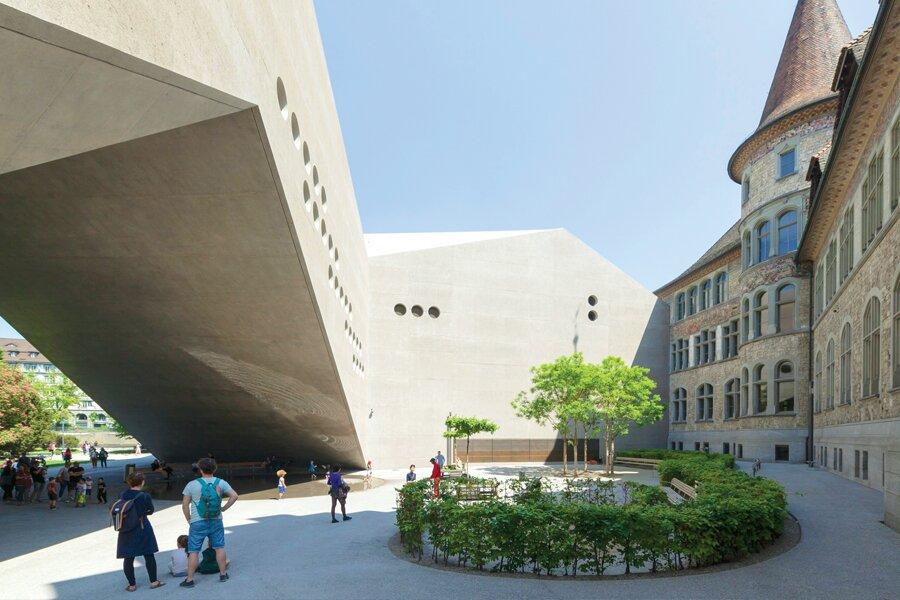 A courtyard with people walking around a building.