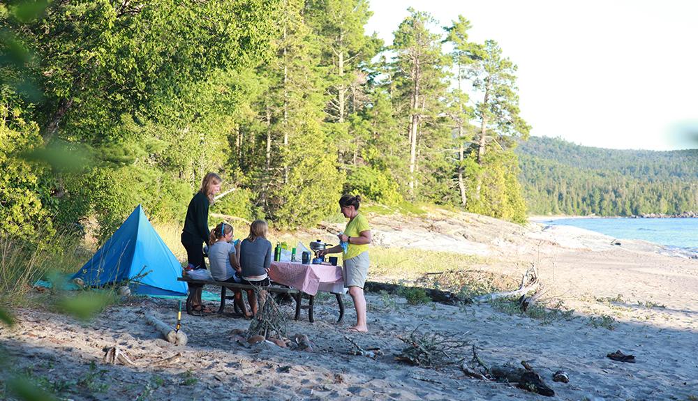 A group of people sitting at a table on the beach.