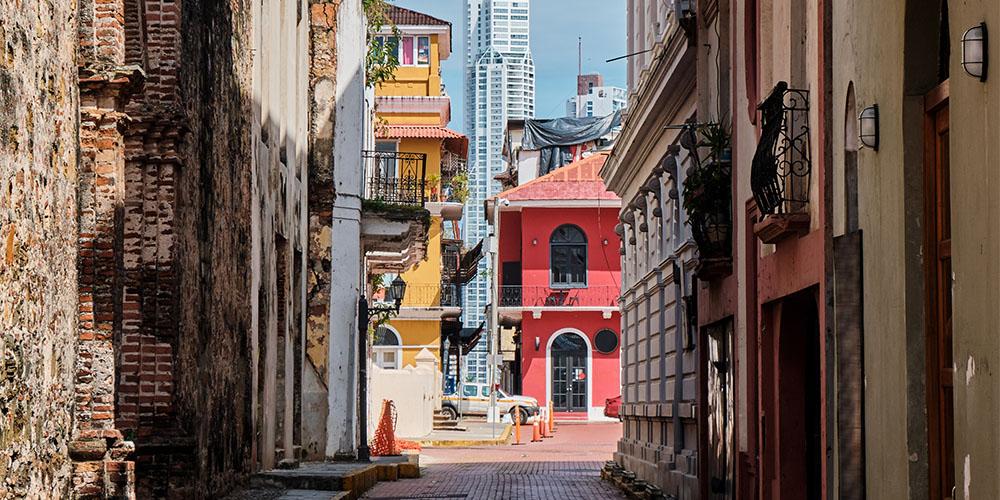 Narrow street with a mix of historic and modern buildings in an urban area.