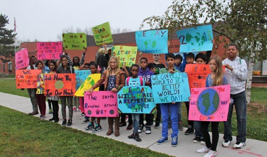 A group of children holding signs on a sidewalk.