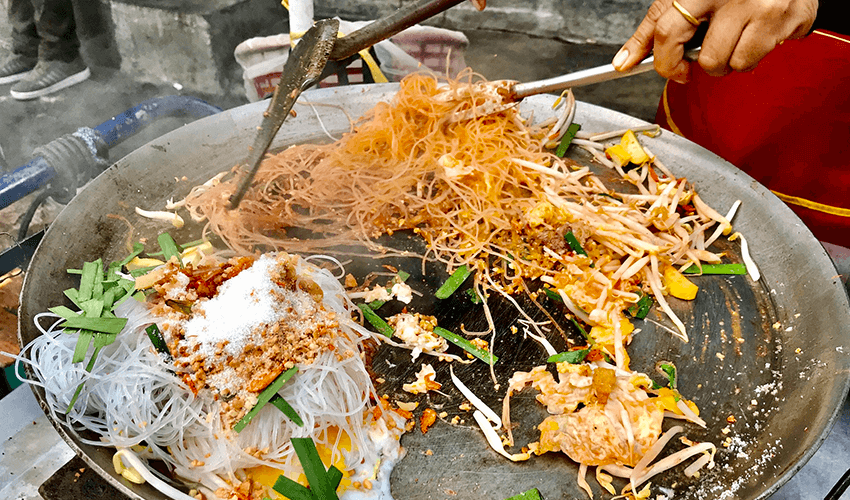 A person is preparing food in a wok.